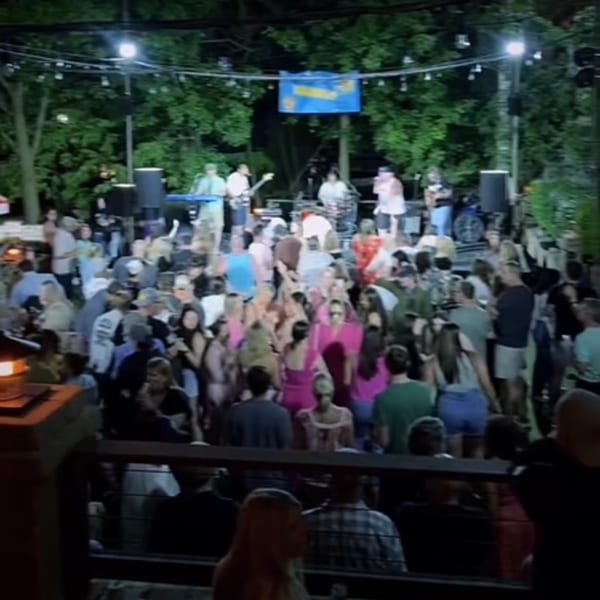 A band performs on an outdoor stage for a large, dancing crowd at Magpie's Den & Pen.